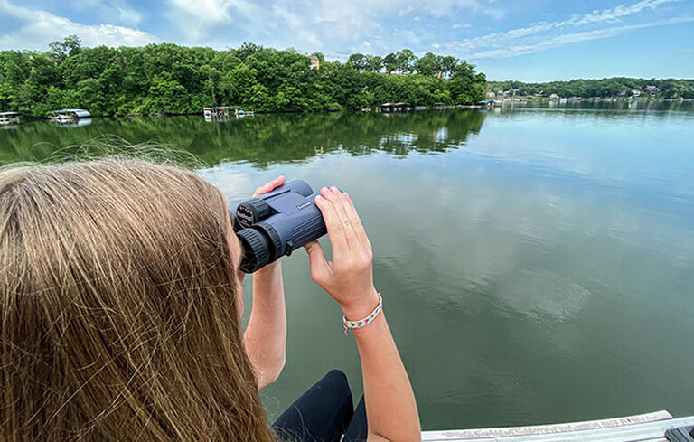 Woman looking through H2O Binoculars on a lake